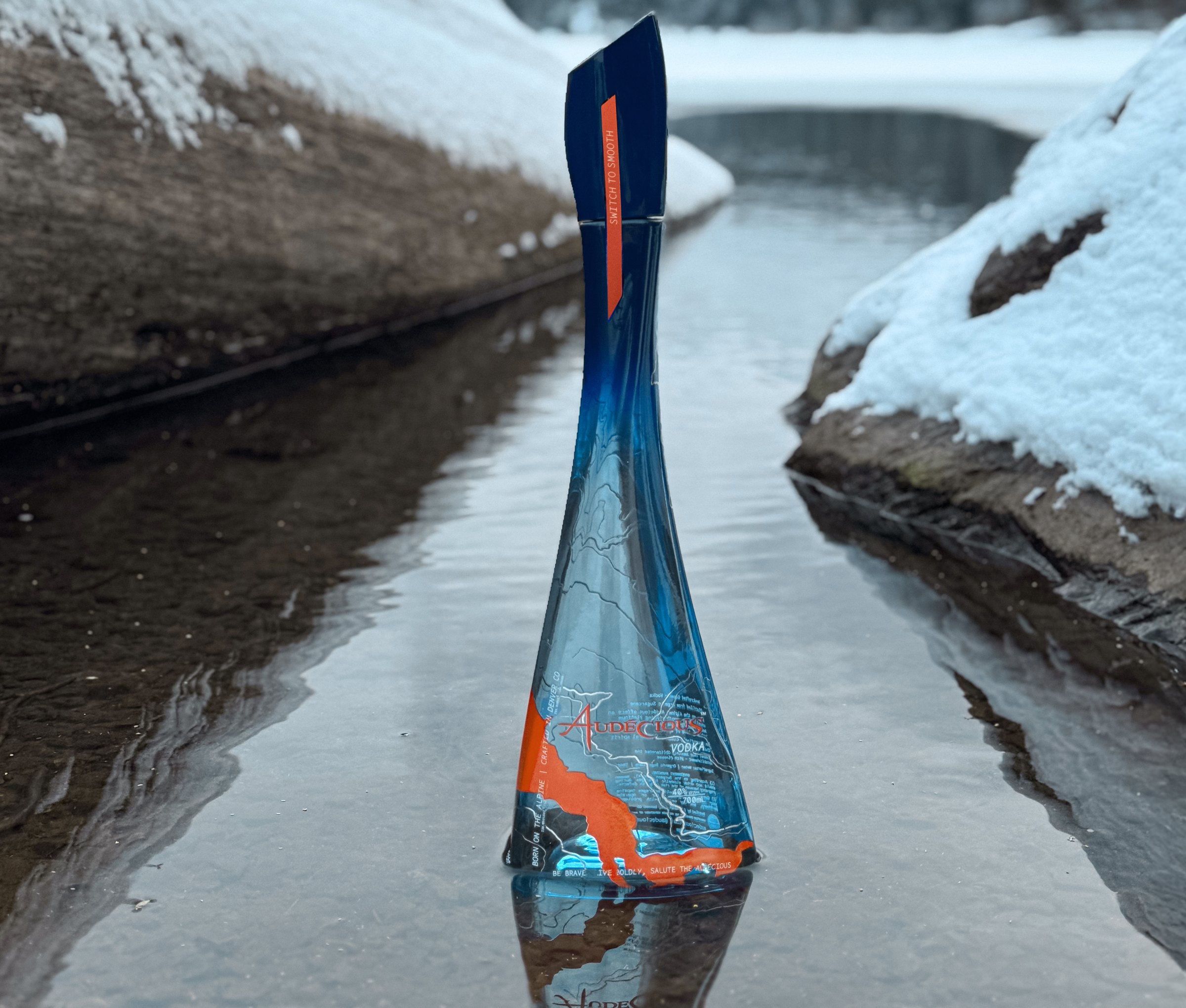 An Audécious bottle standing in meltwater below the Whistler snowline