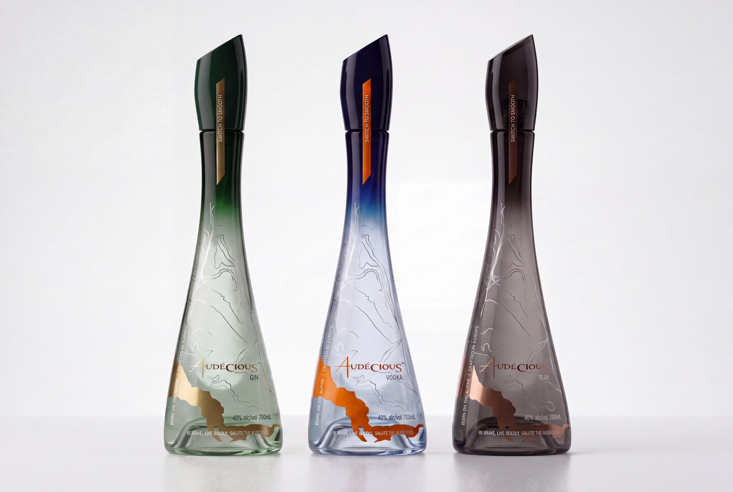 The Audécious range — Gin in dark green with gold, Vodka in blue with orange, Rum in smoked black with bronze